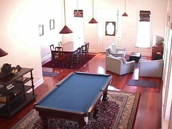 A living room with a pool table, a sofa, and a dining area.