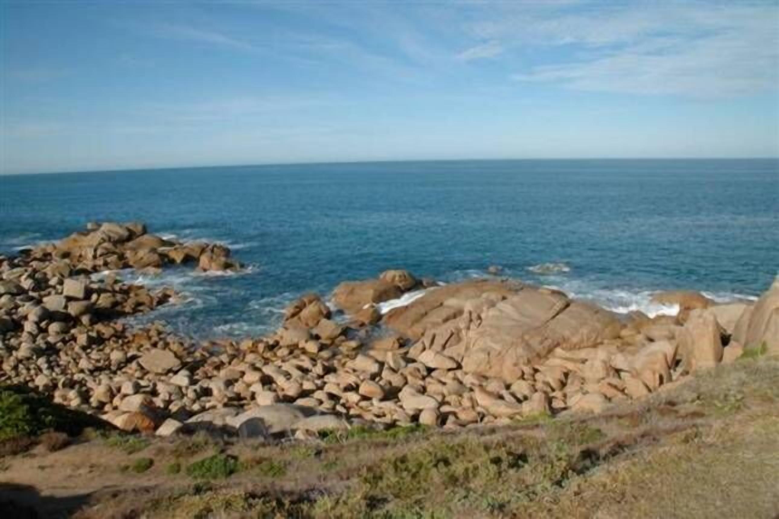 A coastal landscape with rocky terrain and a view of the sea.