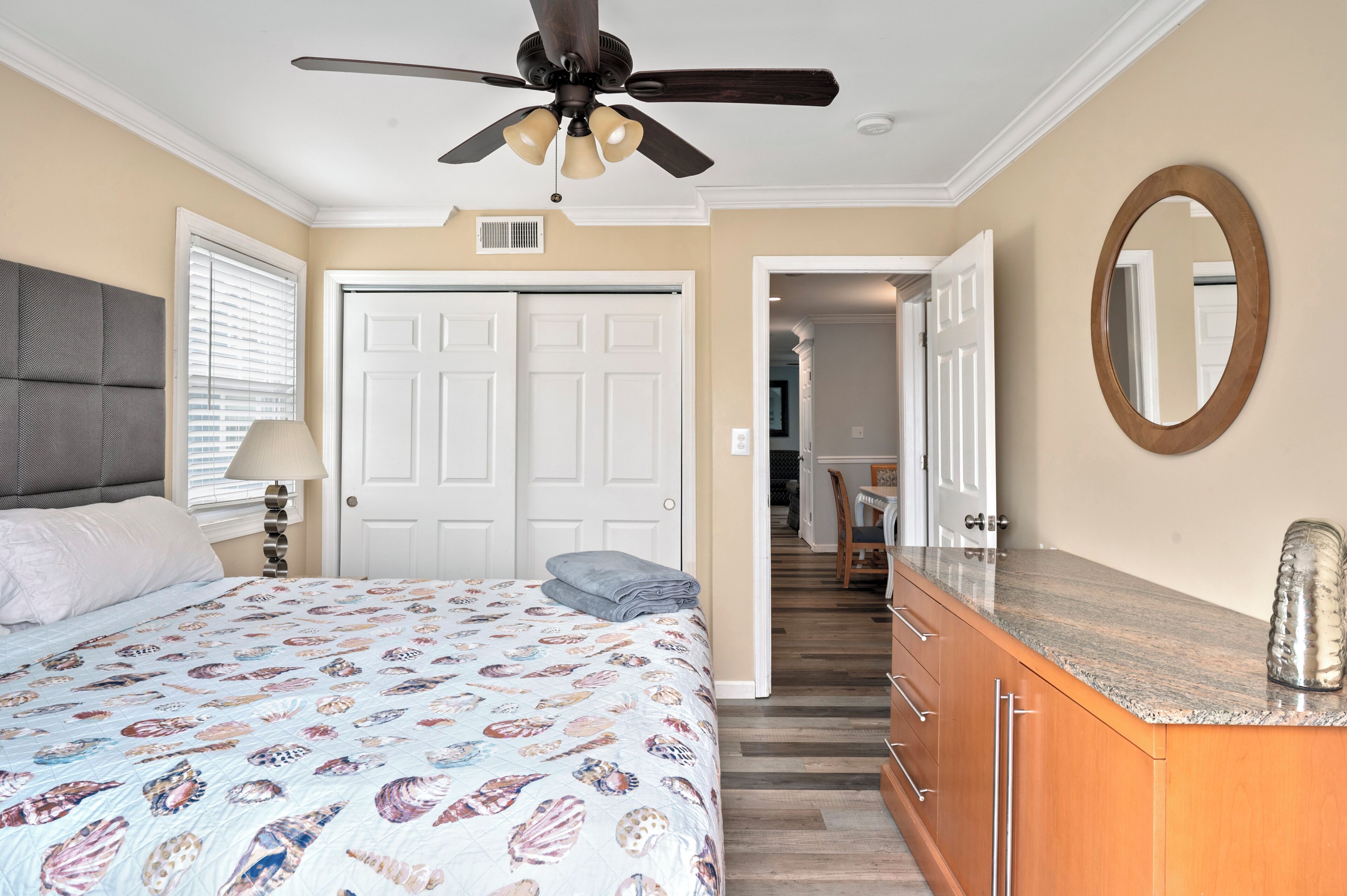 A bedroom with a bed, a ceiling fan, a dresser, and a mirror.