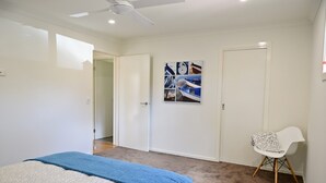 Une chambre à coucher avec un lit, un ventilateur de plafond, une porte et une chaise.