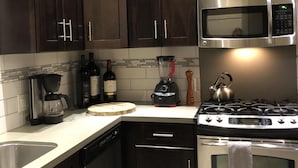 Eine moderne Küche mit dunklen Holzschränken, Edelstahlgeräten, darunter eine Mikrowelle und ein Herd, eine Kaffeemaschine und ein Mixer.