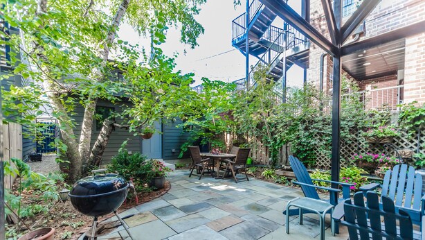 A patio with a grill, outdoor furniture, and a brick wall.
