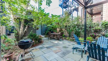 Un patio con una parrilla, muebles de exterior y un muro de ladrillo.