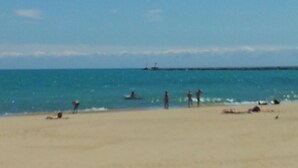 A beach with people sunbathing and swimming.