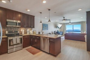A modern kitchen with dark wood cabinets, stainless steel appliances, and a large island.