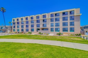 A multi-story hotel with a flat facade, large windows, and a well-maintained lawn in the foreground.