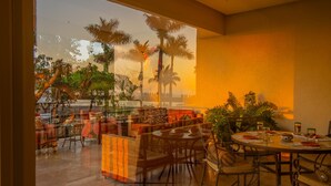 An outdoor seating area with tables and chairs, surrounded by palm trees and plants. - Molino de Agua BEST in PV, amazing location. best pool!  Walk EVERYWHERE (Puerto Vallarta)