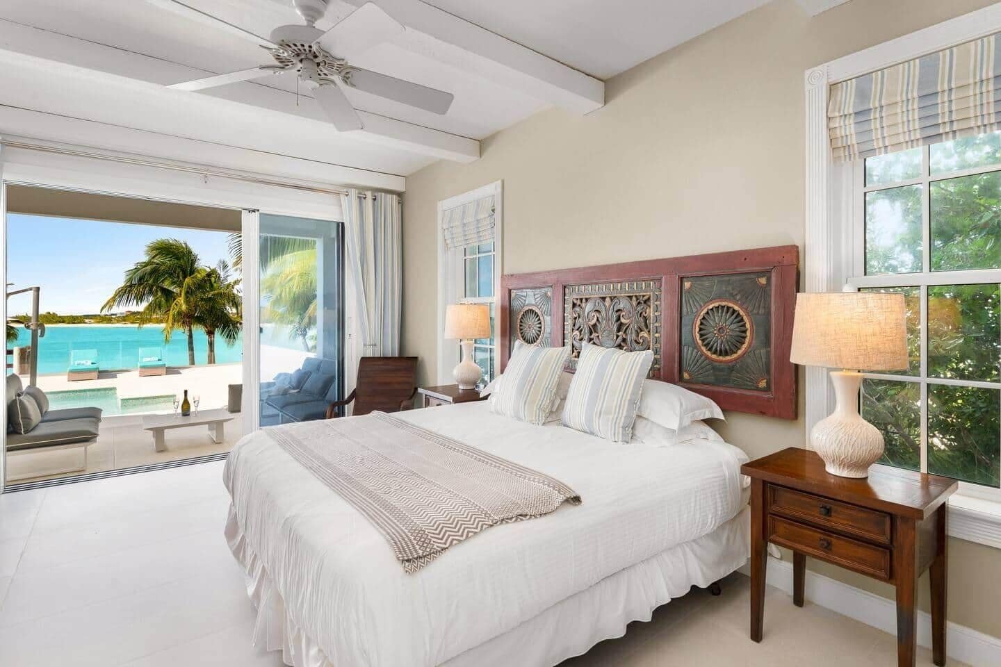 A spacious bedroom with a large bed, a ceiling fan, and a view of the ocean.