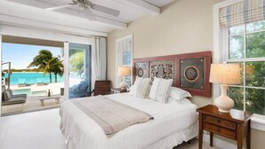 A spacious bedroom with a large bed, a ceiling fan, and a view of the ocean.