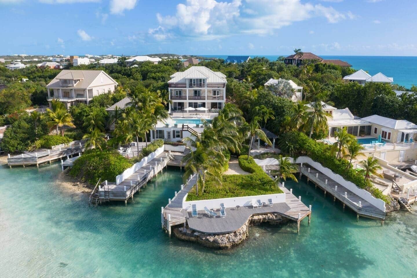 A resort with multiple overwater bungalows connected by walkways, clear turquoise water, and a view of the ocean.