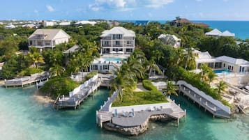 A resort with multiple overwater bungalows connected by walkways, clear turquoise water, and a view of the ocean.