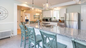A modern kitchen with a central island, stainless steel appliances, and teal chairs. - Gorgeous home: walk to beach, harbor, cliff walk, wiggly bridge, dining etc. (York Harbor)