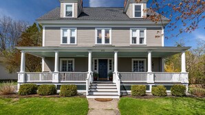 A two-story house with a front porch, a central entrance, and a small front yard. - Gorgeous home: walk to beach, harbor, cliff walk, wiggly bridge, dining etc. (York Harbor)