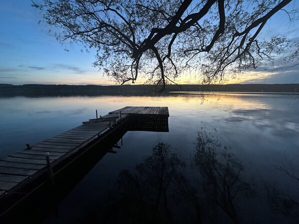 Une jetée en bois s’étendant sur une étendue d’eau calme, avec un arbre qui la surplombe.