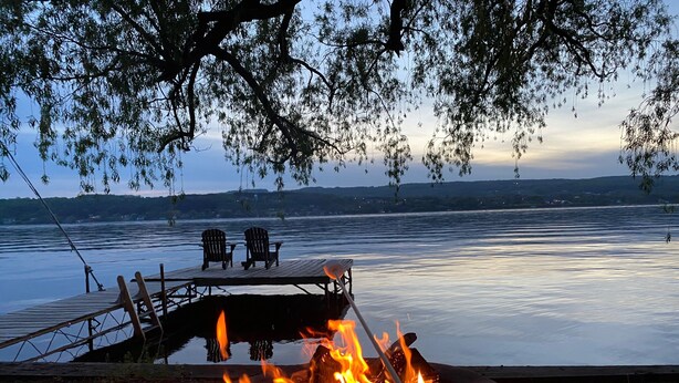 Une terrasse au bord du lac, avec un foyer et deux chaises donnant sur l’eau.