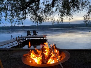 Une terrasse au bord du lac, avec un foyer et deux chaises donnant sur l’eau.