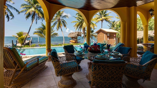 A covered outdoor seating area with wicker furniture, a pool, and a view of the ocean. - Luxury, Beachfront, Home with Resort-amenities, Housekeeping & FREE GOLF CART. (Hopkins)