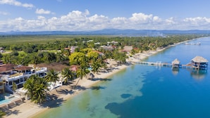 A coastal resort with beachside villas, a swimming pool, and a pier extending into the water. - Luxury, Beachfront, Home with Resort-amenities, Housekeeping & FREE GOLF CART. (Hopkins)