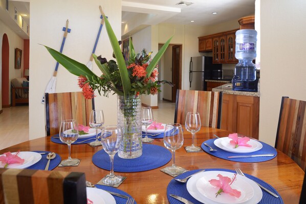A dining table set with blue placemats, white plates, and clear glassware. - Luxury, Beachfront, Home with Resort-amenities, Housekeeping & FREE GOLF CART. (Hopkins)