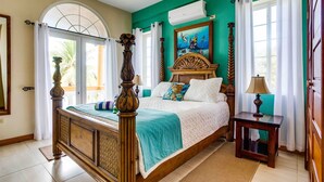 A bedroom with a wooden bed, teal walls, a painting, and a window with curtains. - Luxury, Beachfront, Home with Resort-amenities, Housekeeping & FREE GOLF CART. (Hopkins)