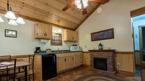 A kitchen with wooden cabinets, a microwave, a coffee maker, and a fireplace.
