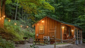 A wooden cabin with a porch, a bench, and a table.