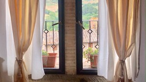 Un balcon doté de deux fenêtres en arc, chacune offrant une vue sur un paysage rural.