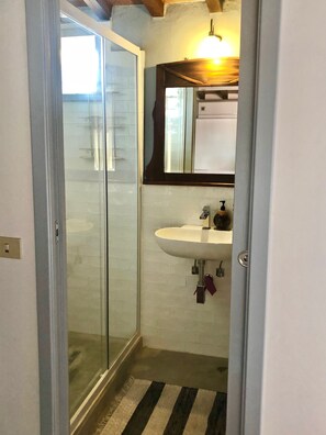 A bathroom with a glass shower enclosure, a sink, and a mirror. - Enchanting Tuscany Vacation Rental in Medieval Fortress Town Panoramic Views (Barberino Val D'elsa)