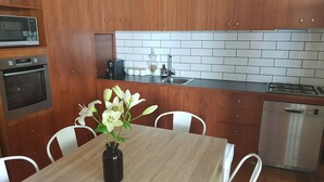 Eine moderne Küche mit Holzausstattung, Backofen, Geschirrspüler von Bosch und einer weißen Fliesenspiegel.