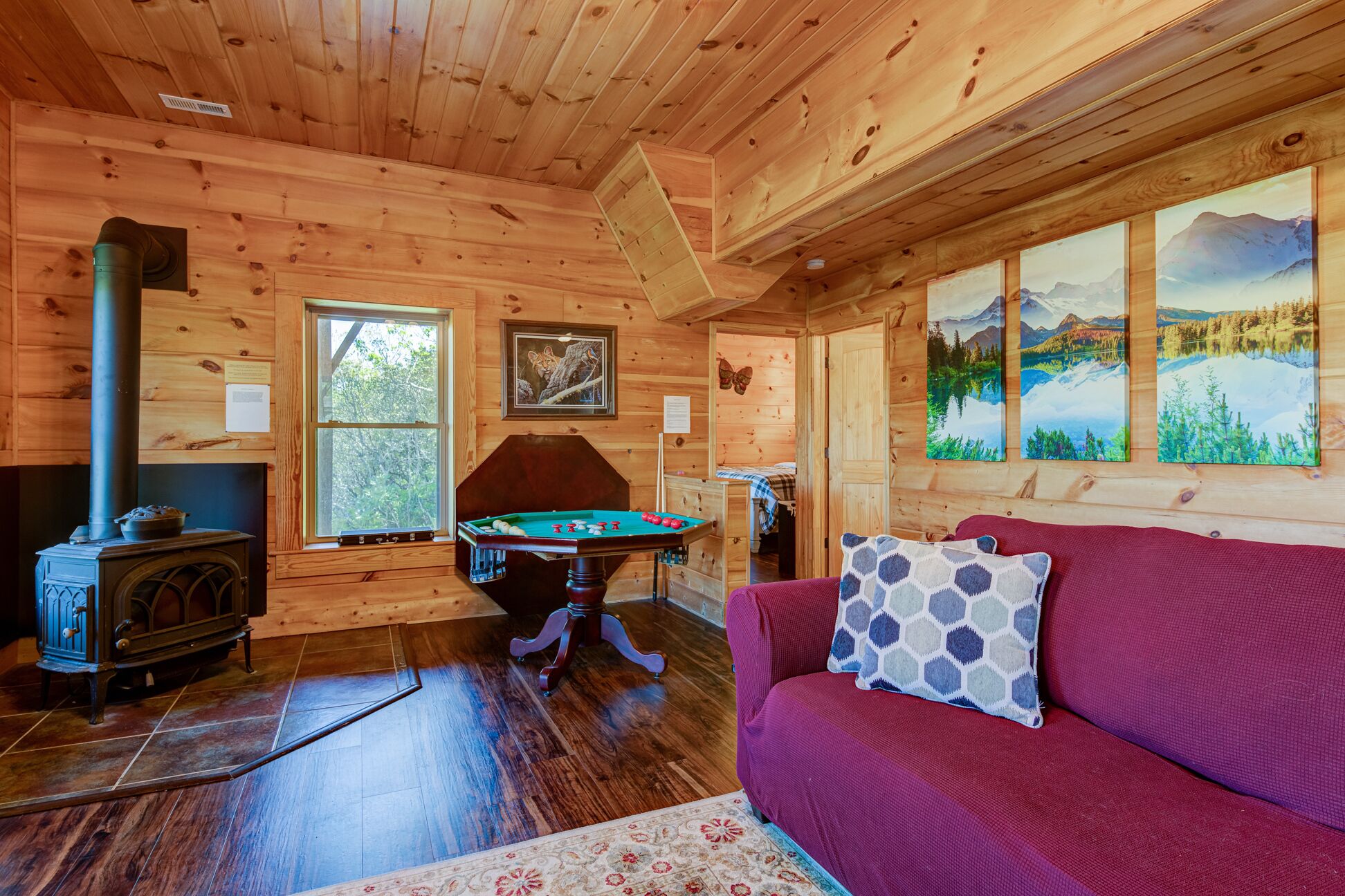 A cozy cabin interior with a wooden interior, a pool table, a sofa, and a fireplace.