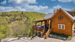 Una cabaña de madera con terraza, jacuzzi y vistas panorámicas a la montaña.