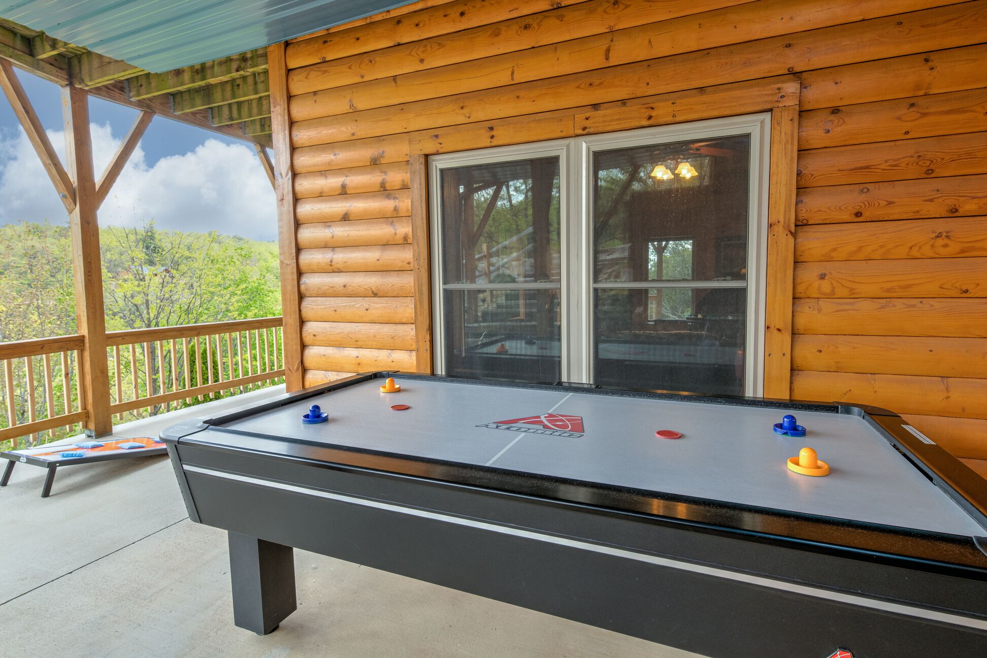 Une table de baby-foot dans un chalet en bois doté d’un balcon donnant sur une zone boisée.
