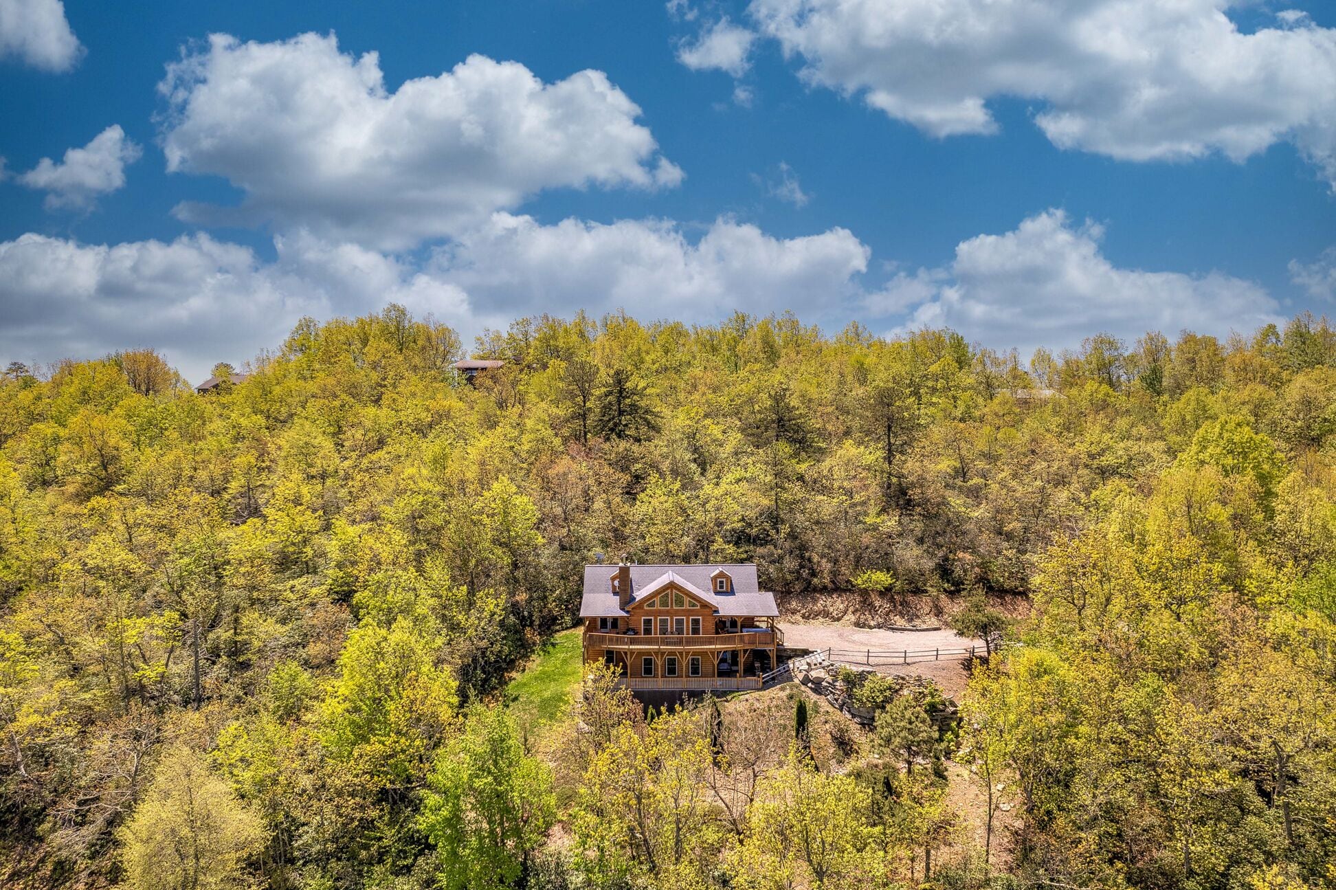 Una casa de madera grande rodeada de un bosque frondoso, bajo un cielo despejado.