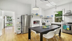 A modern kitchen with a central island, stainless steel appliances, and white cabinetry. - Wisteria Cottage - opposite beach (Indented Head)