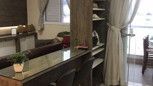 Moderni keittiö, jossa on lasinen ruokapöytä, tummat tuolit ja ruukussa oleva kasvi.