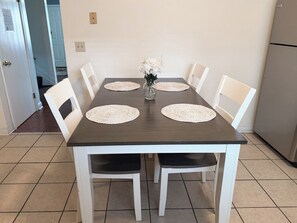 Une table à manger avec quatre chaises, deux sets de table et un vase avec des fleurs.