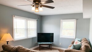 Un salon doté d’un ventilateur de plafond, d’un téléviseur à écran plat, de deux canapés et d’une lampe.