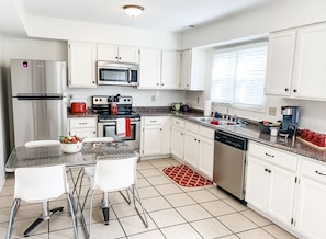 A modern kitchen with white cabinets, stainless steel appliances, a marble countertop, and a dining area with white chairs. - Location, location, location!  In Oxford's Mile Square!  4 Bed/2 Bath Townhouse (Oxford)