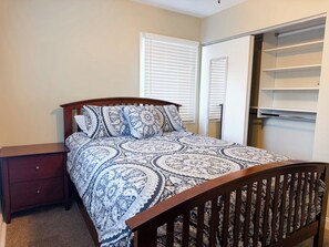 A bedroom with a bed, nightstand, and built-in closet with shelves.