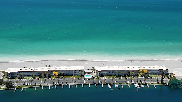 Vue aérienne d’un hôtel avec une plage et un port de plaisance.