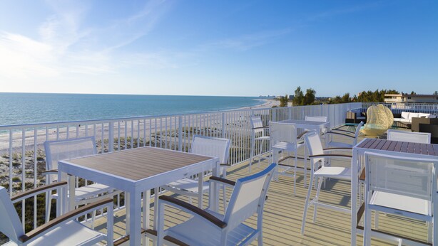 A deck with white furniture and a view of the sea.