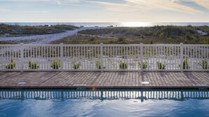 Une piscine avec vue sur la plage et les dunes.