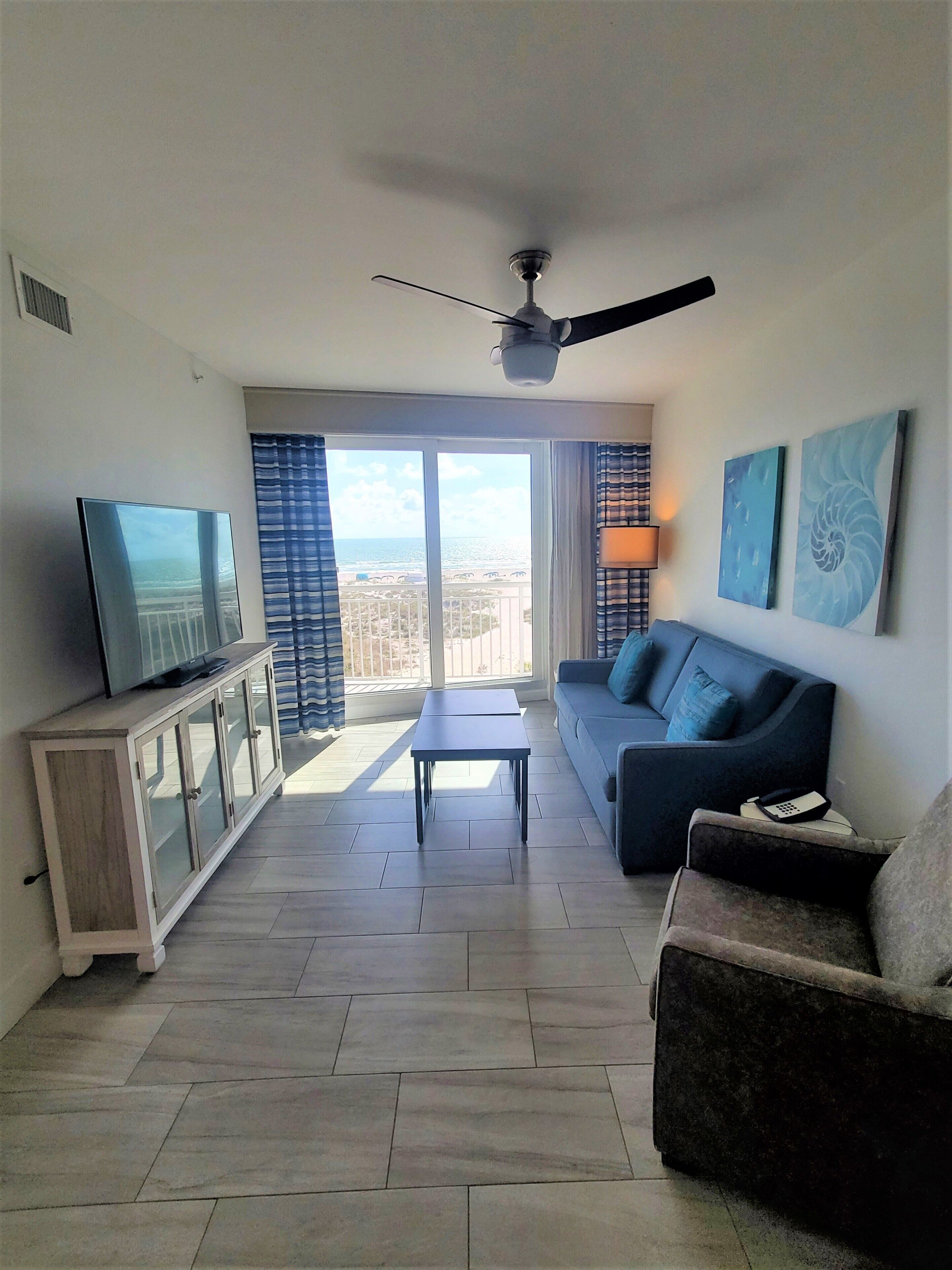 A living room with a television, sofa, and a ceiling fan.