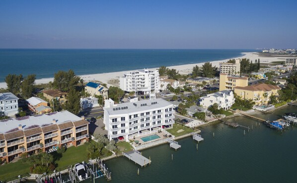 Une ville côtière dotée d’un port de plaisance, d’une plage et de divers bâtiments, dont un hôtel à plusieurs étages et doté de balcons.