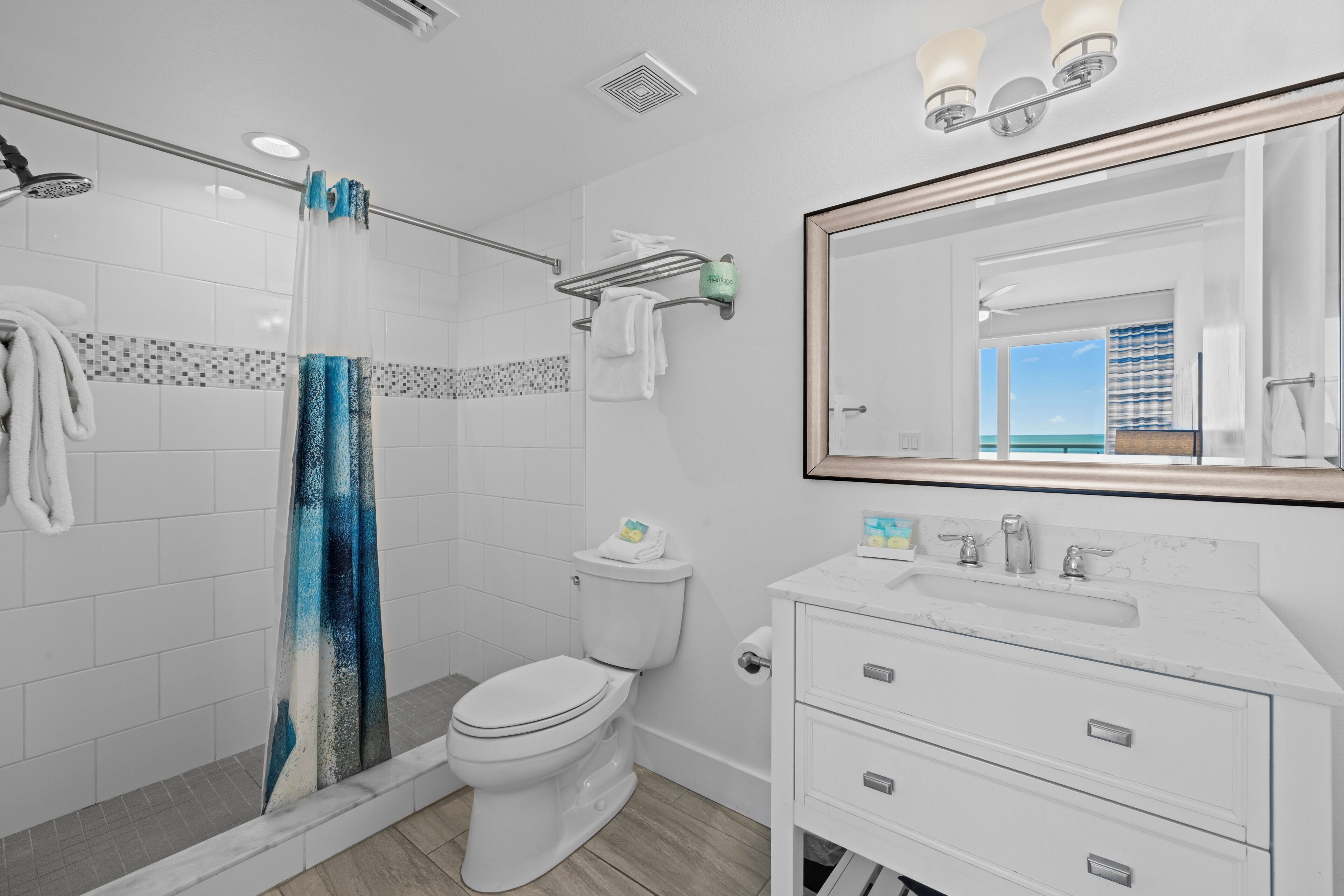 A modern bathroom with a shower, toilet, vanity, and a large mirror.