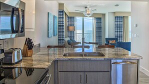 A modern kitchen with a built-in oven, a stainless steel refrigerator, and a granite countertop.