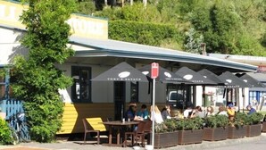 A small outdoor seating area with tables and chairs, a covered patio, and a sign for 'Toby's Estate'. - Amberlyn Escapes Killcare (Killcare Heights)