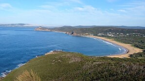A coastal landscape with a beach, grassy hills, and a clear sky. - Amberlyn Escapes Killcare (Killcare Heights)