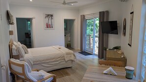 A bedroom with a bed, a desk, a TV, and a sliding glass door leading to a balcony. - Amberlyn Escapes Killcare (Killcare Heights)