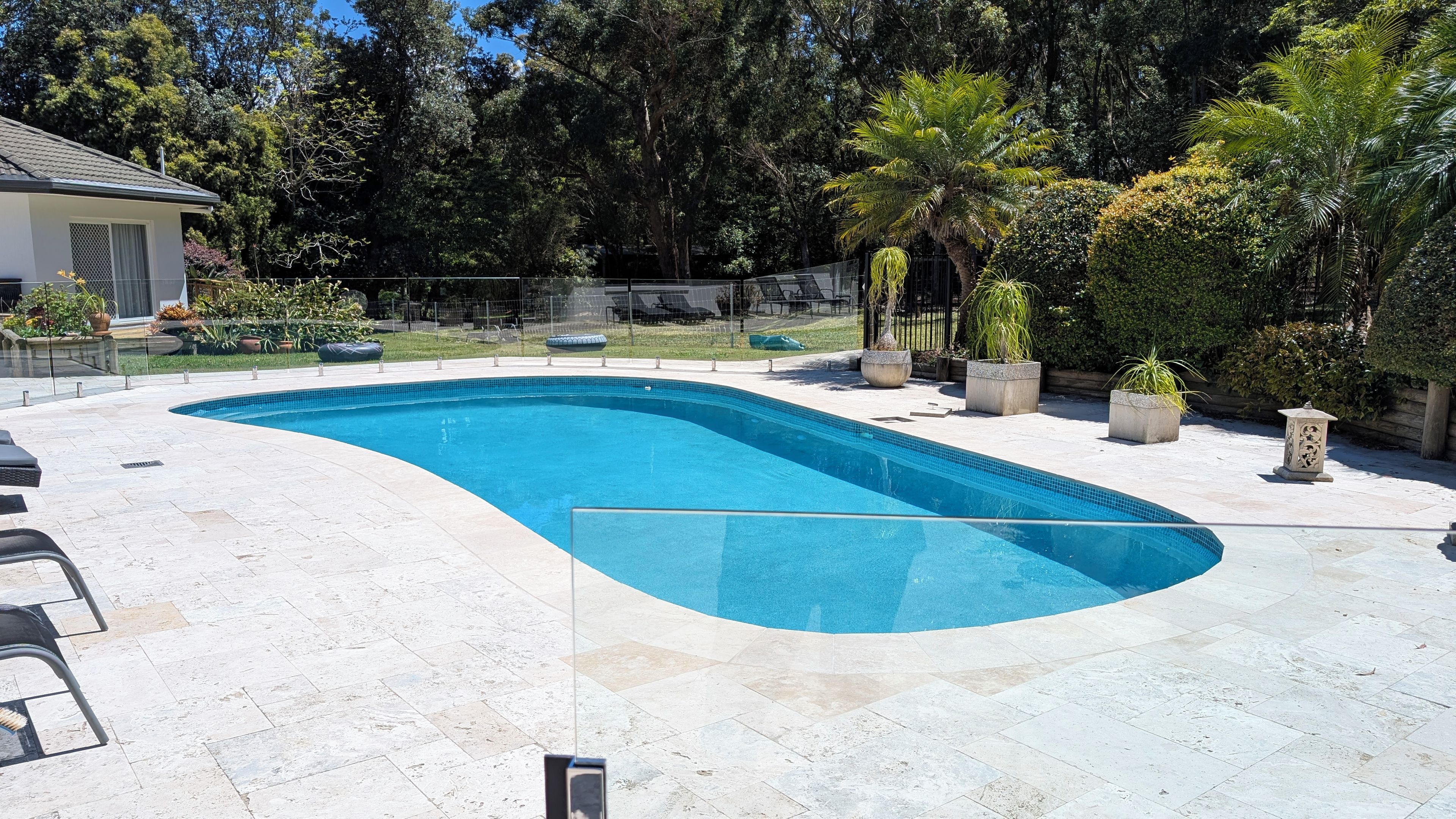 A swimming pool with a curved edge, surrounded by a paved deck.
